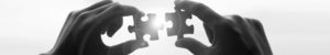 Two hands with a jigsaw puzzle piece in each